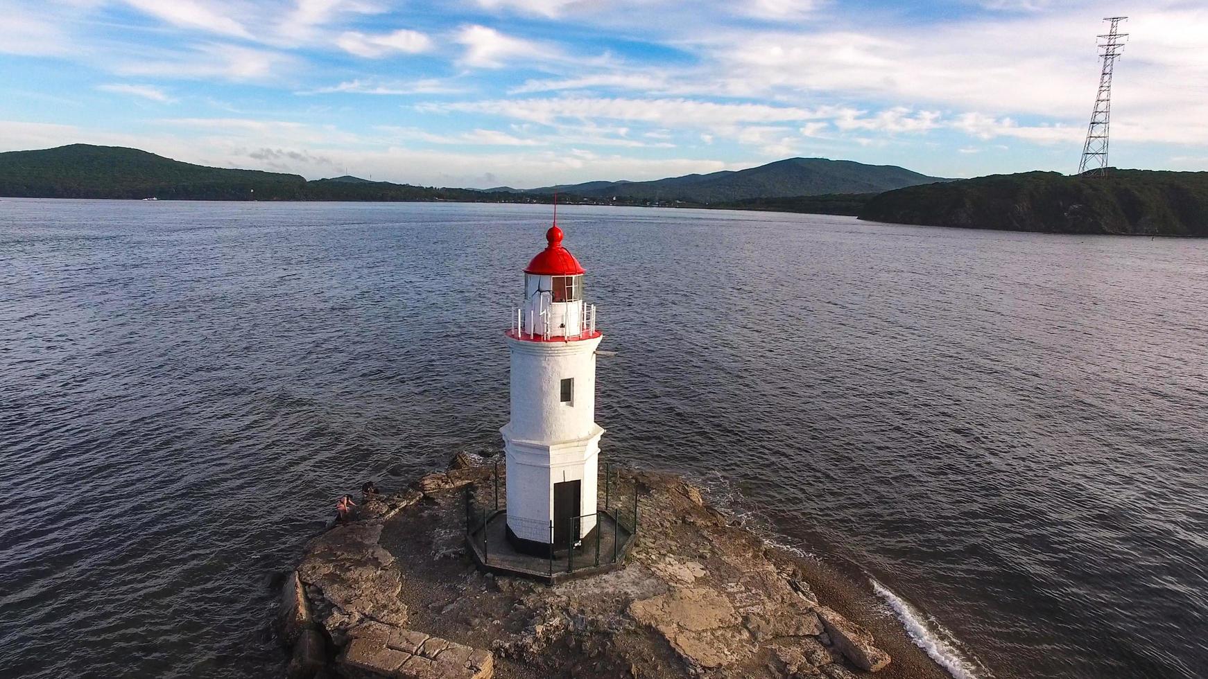 zeegezicht met een vuurtoren naast waterlichaam met bewolkte blauwe hemel in Vladivostok, Rusland foto