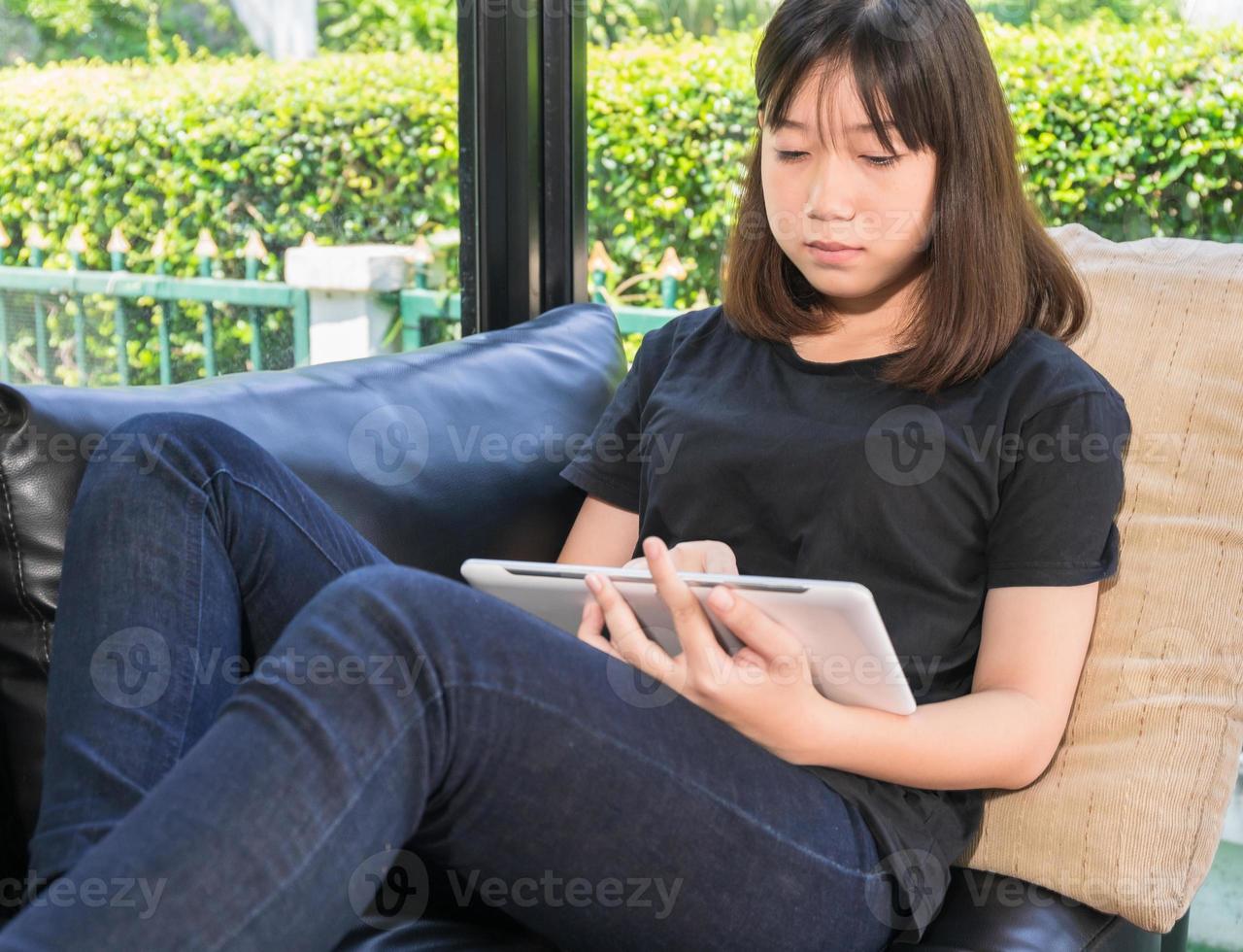 jong meisje aan het studeren online van digitaal tablet in leven kamer foto