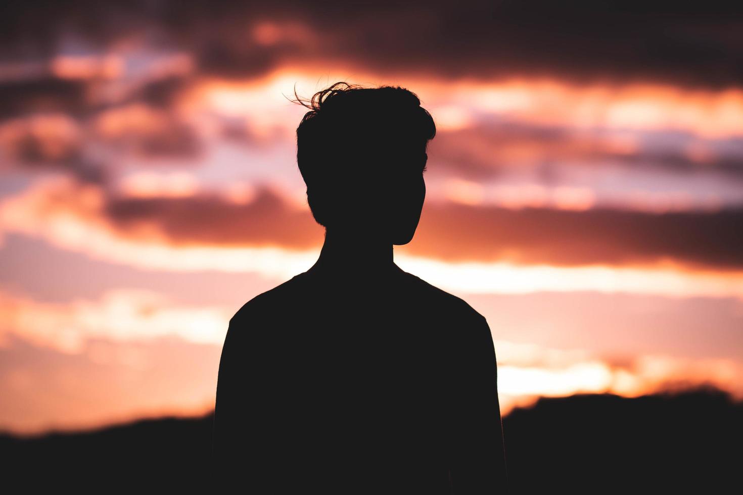 silhouet man tegen kleurrijke bewolkte zonsondergang foto