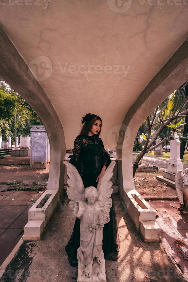 een Aziatisch vrouw gekleed allemaal in zwart en een eng gezicht was staand over- de begraafplaats foto