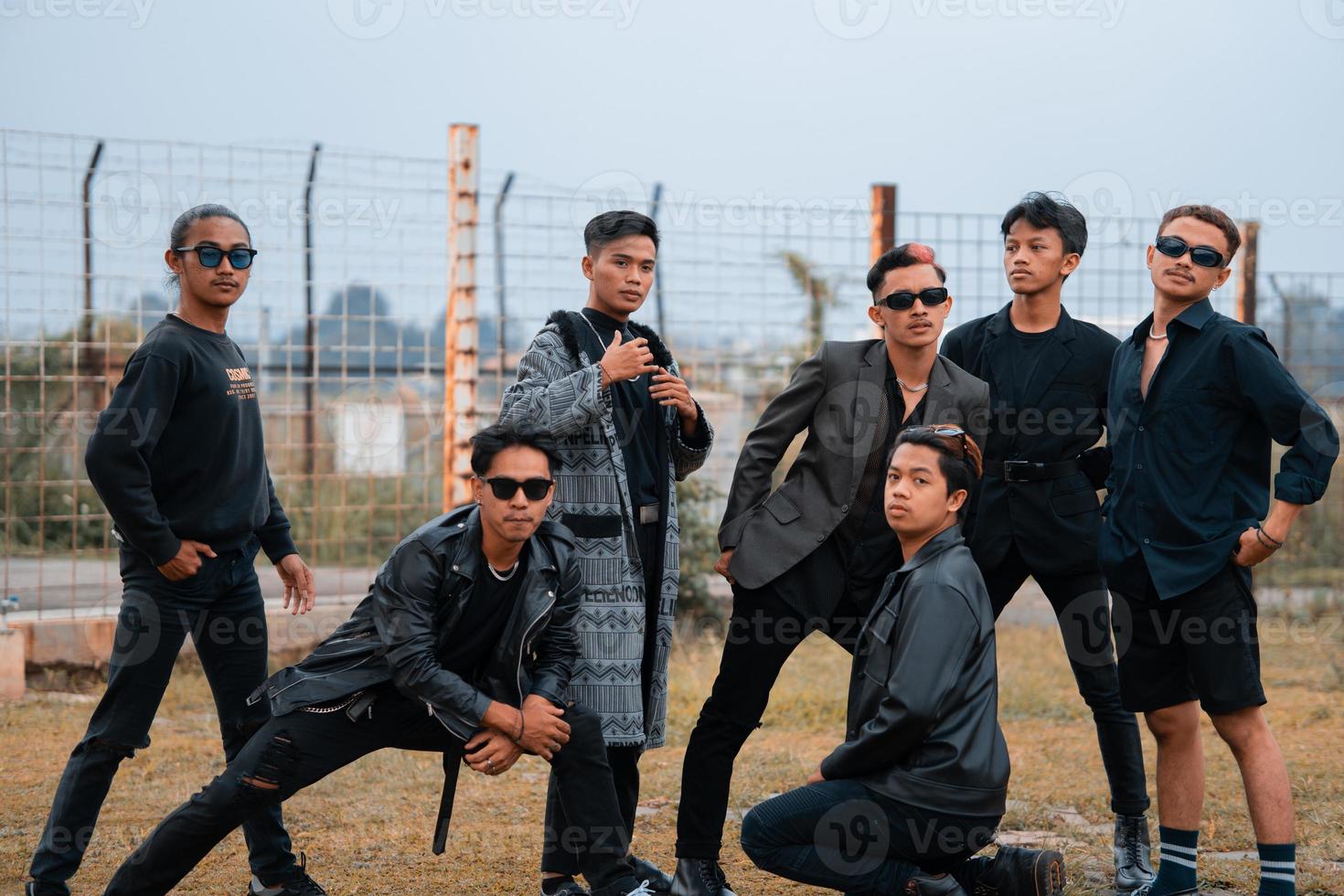 een groep van tiener- jongens in zwart kleren poseren heel galant met hun vrienden in een veld- foto