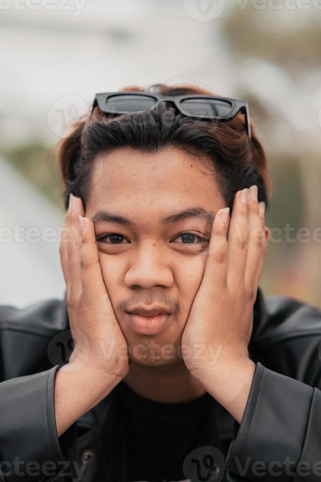 de gezicht van een heel dwaas Aziatisch Mens met zonnebril Aan zijn hoofd terwijl ontspannende in een cafe foto