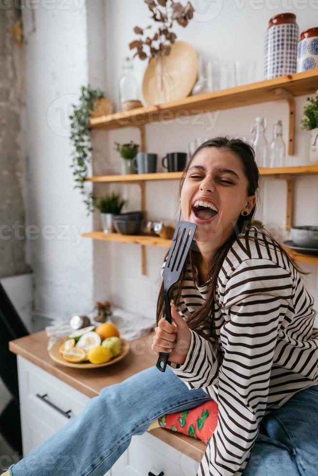 grappig vrouw het zingen in spatel, Holding spatel net zo microfoon. foto