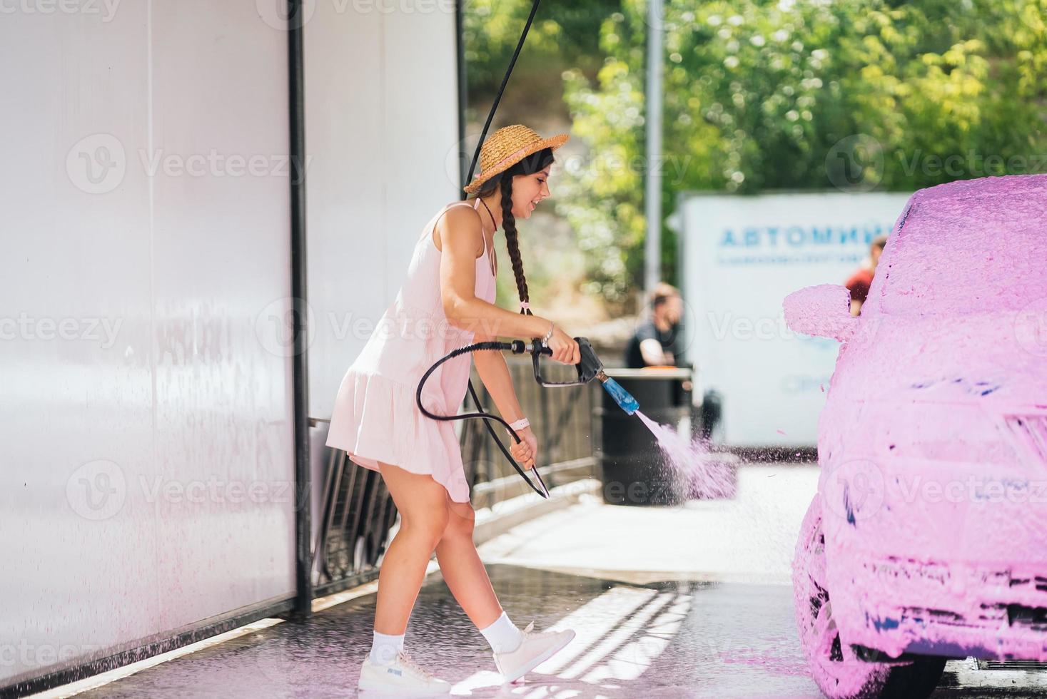 brunette van een hoge druk slang is van toepassing een schoonmaakster Aan de auto foto