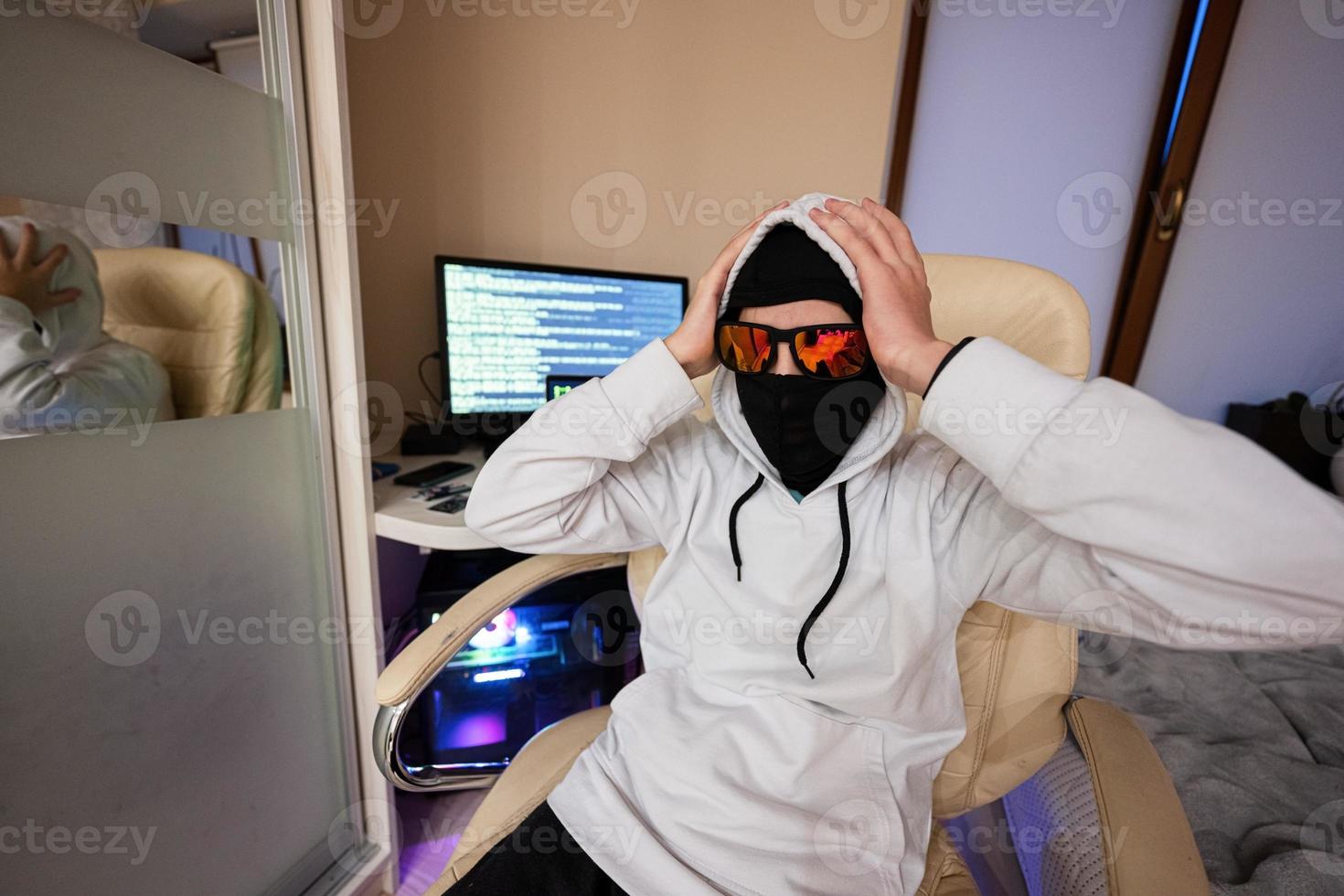 jongen hacker gepakt zijn hoofd. internet diefstal . Mens vervelend een bivakmuts za achter een laptop. foto