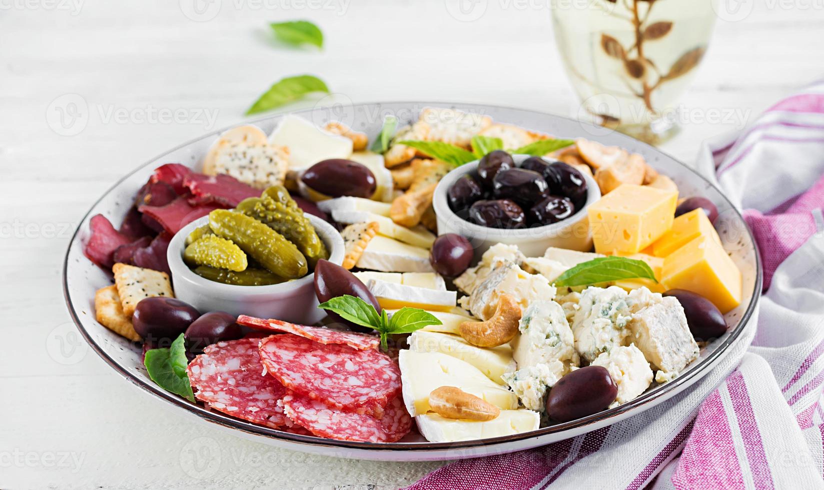 antipasto schotel met basturma, salami, blauw kaas, noten, augurken en olijven Aan een wit houten achtergrond. foto