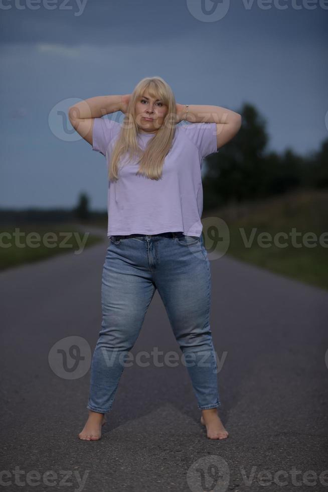 mollig midden- oud vrouw poseren in jeans Aan de straat, te zwaar xxl. een vol meisje geniet leven. foto