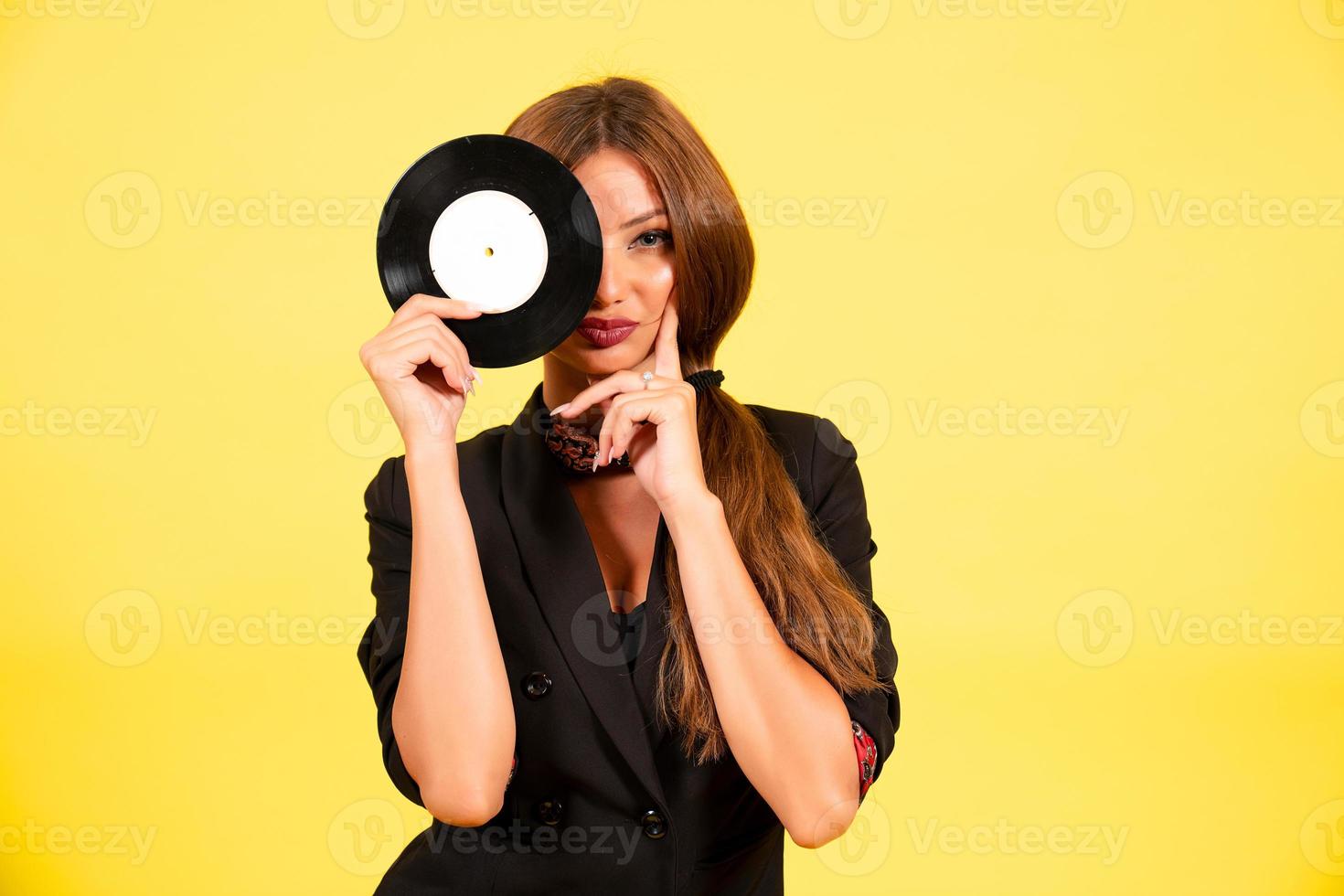 meisje in een zwart pak Aan een geel achtergrond met een Vermelding in haar handen, muziek, de meisje shows emoties foto
