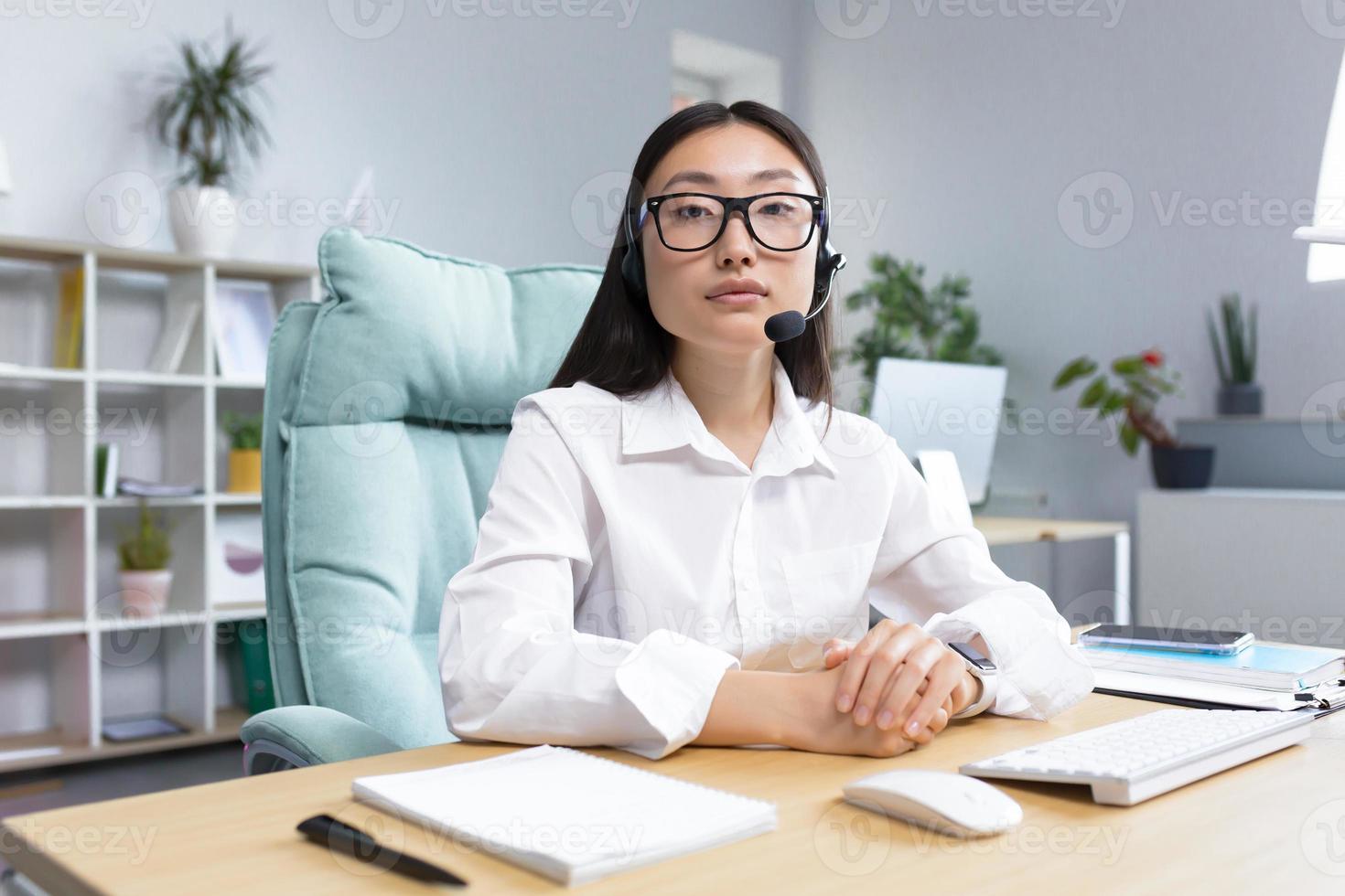 portret van een jong mooi Aziatisch vrouw in bril en hoofdtelefoons met een microfoon foto