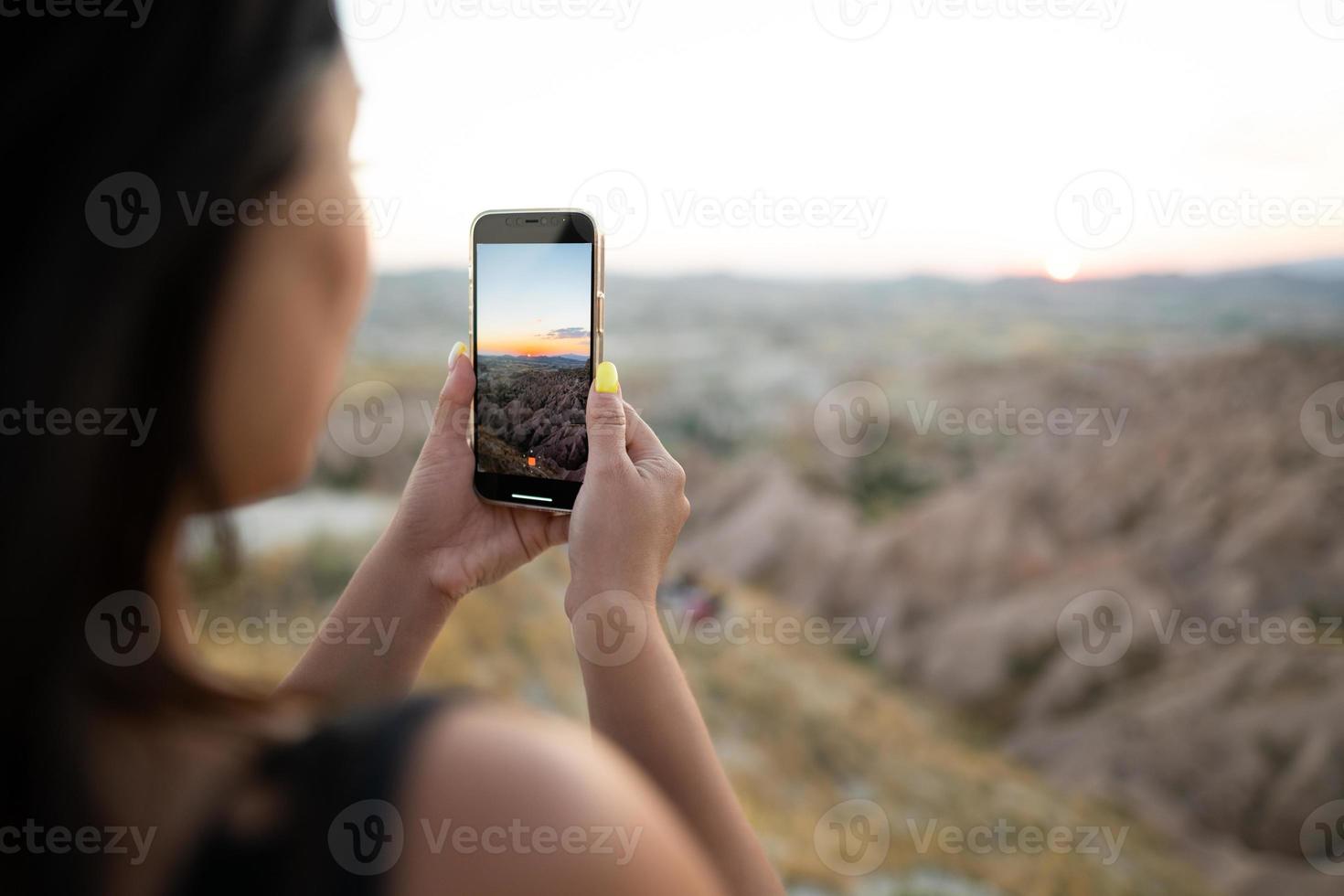 een toerist duurt afbeeldingen van de zonsondergang in de bergen Aan een mobiel telefoon foto