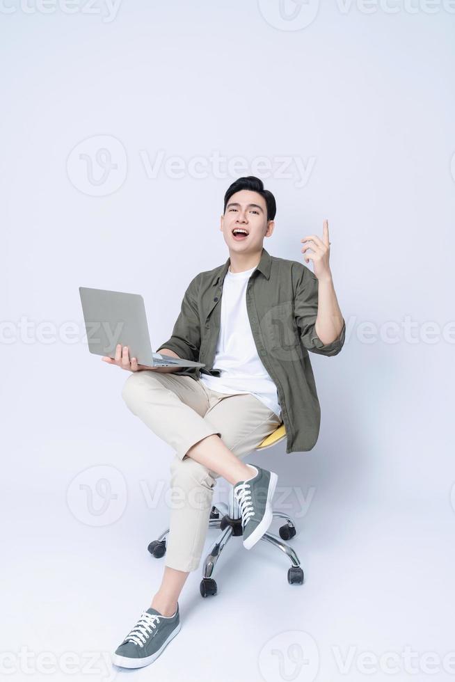 jong Aziatisch bedrijf Mens zittend Aan stoel en gebruik makend van laptop Aan achtergrond foto