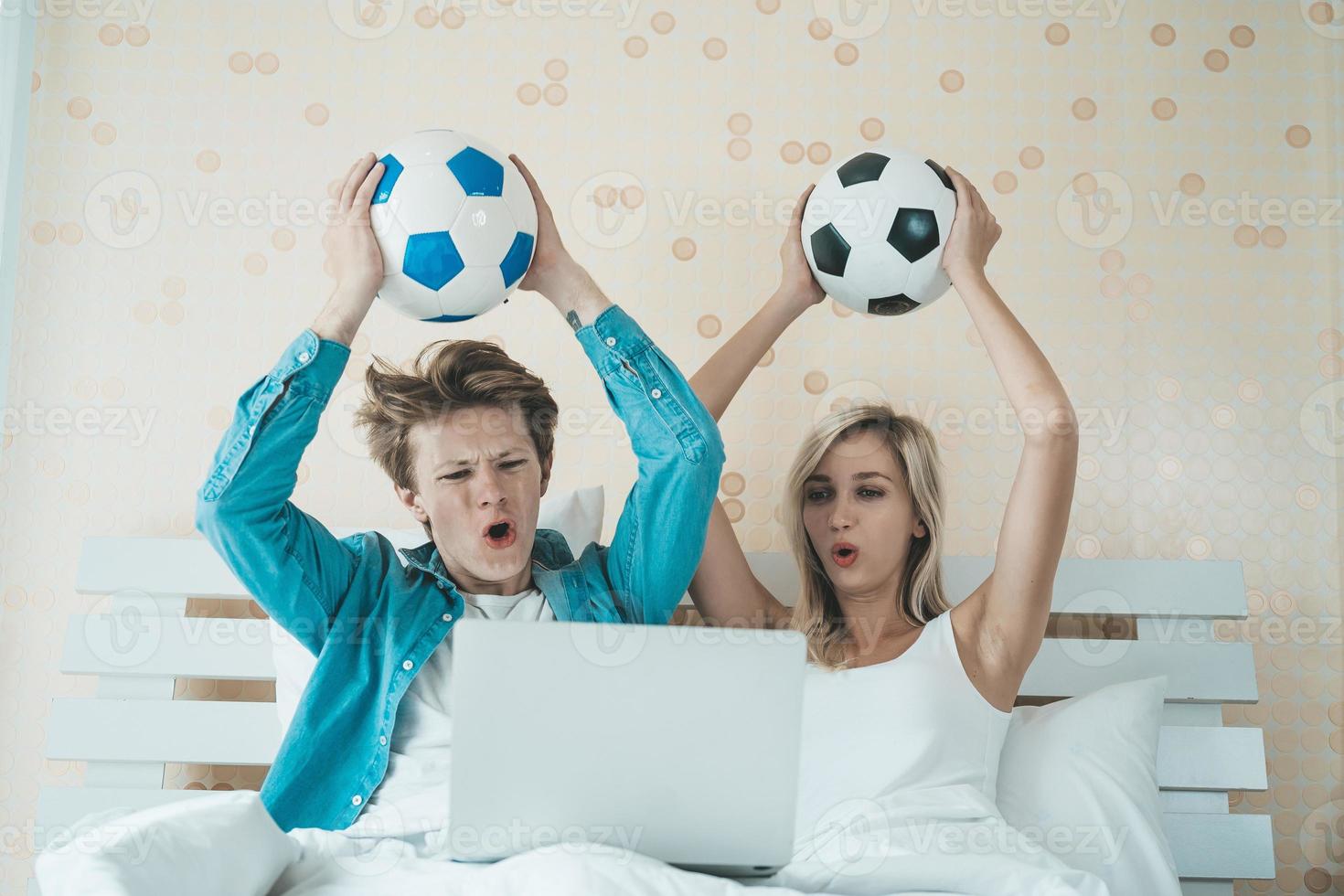 gelukkige paar voetbal kijken op het bed foto