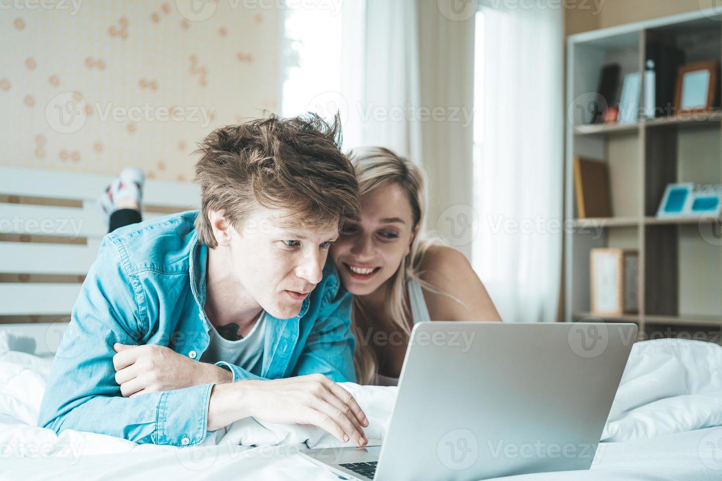 gelukkige paar met laptopcomputer op het bed foto
