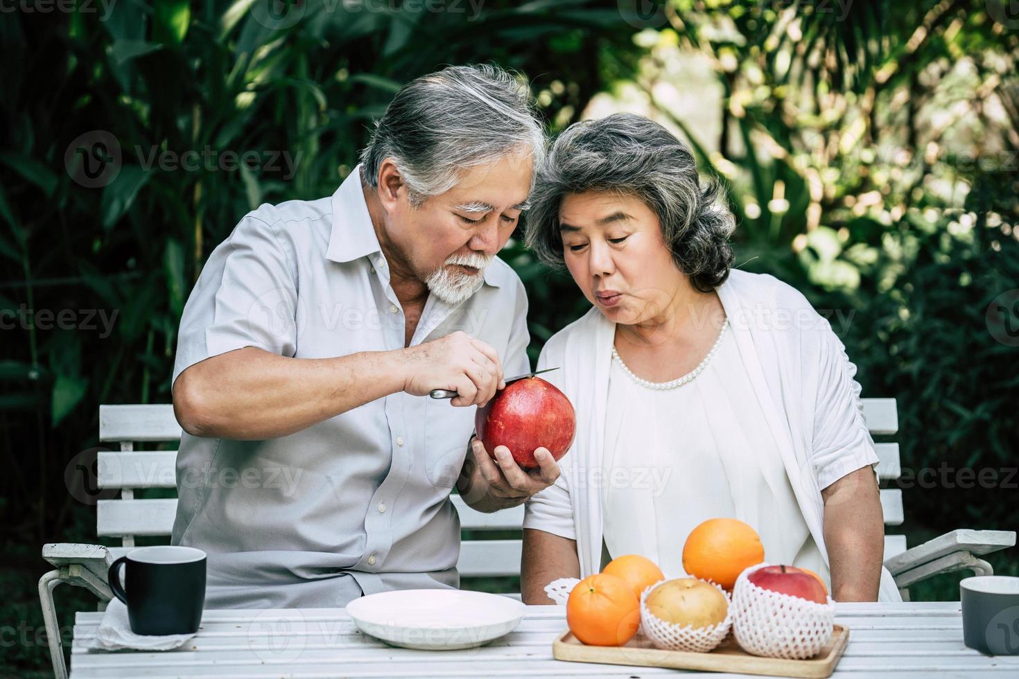 bejaarde echtpaar snijden en eten van fruit foto