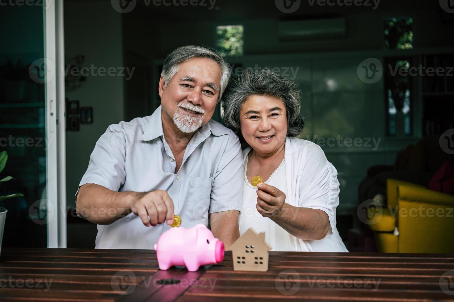 bejaarde echtpaar praten over financiën met spaarvarken foto