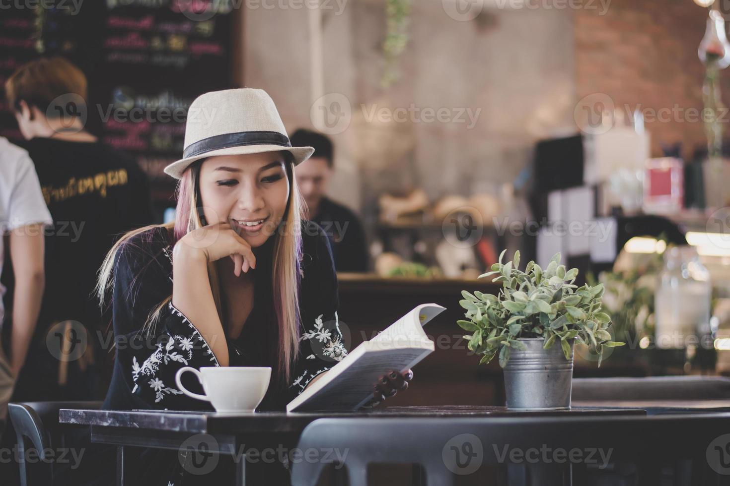 gelukkig zakenvrouw lezen van een boek terwijl u ontspant in café foto