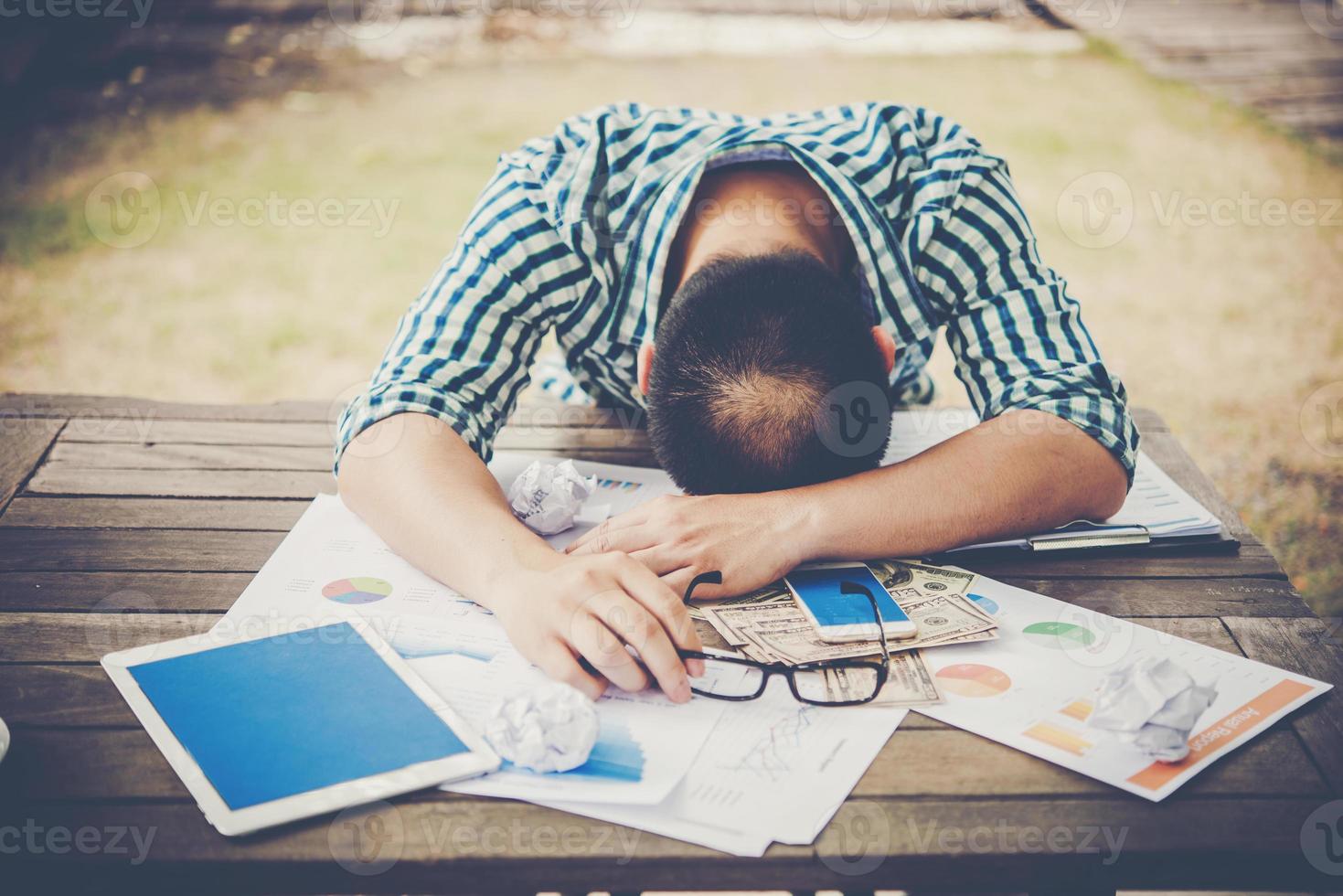 moe werkende man slapen op de werkplek vol werk foto