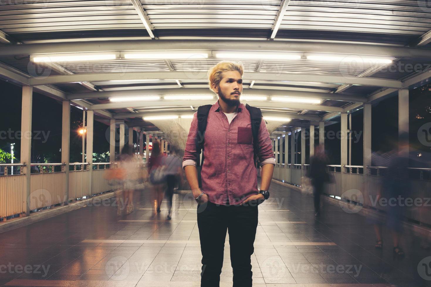 knappe bebaarde man met rugzak staande op straat 's nachts reizen foto