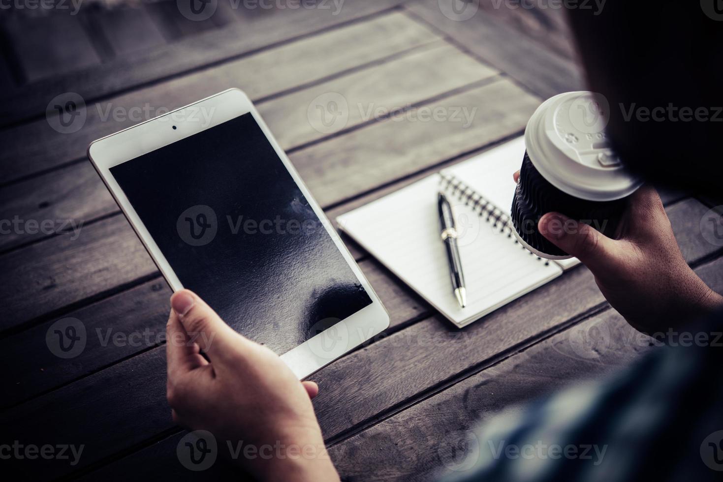 jonge man met behulp van digitale tablet terwijl het drinken van koffie om thuis te zitten tuin foto