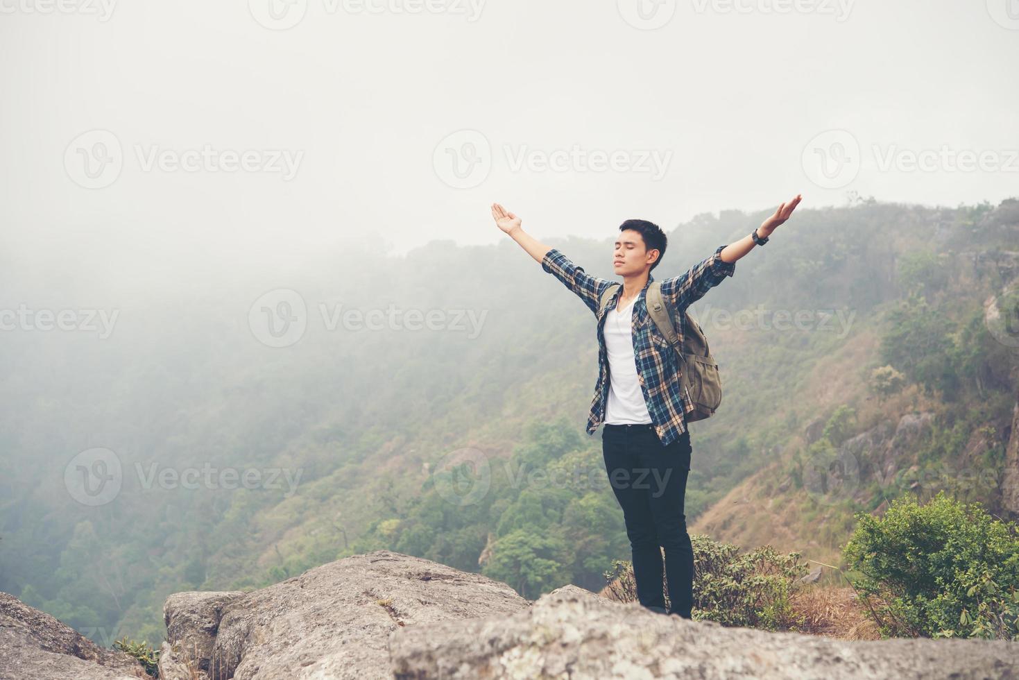 wandelaar met rugzak staande op de top van een berg met opgeheven handen foto