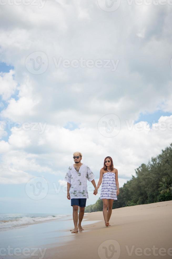 jonge gelukkige paar wandelen op het strand glimlachen foto