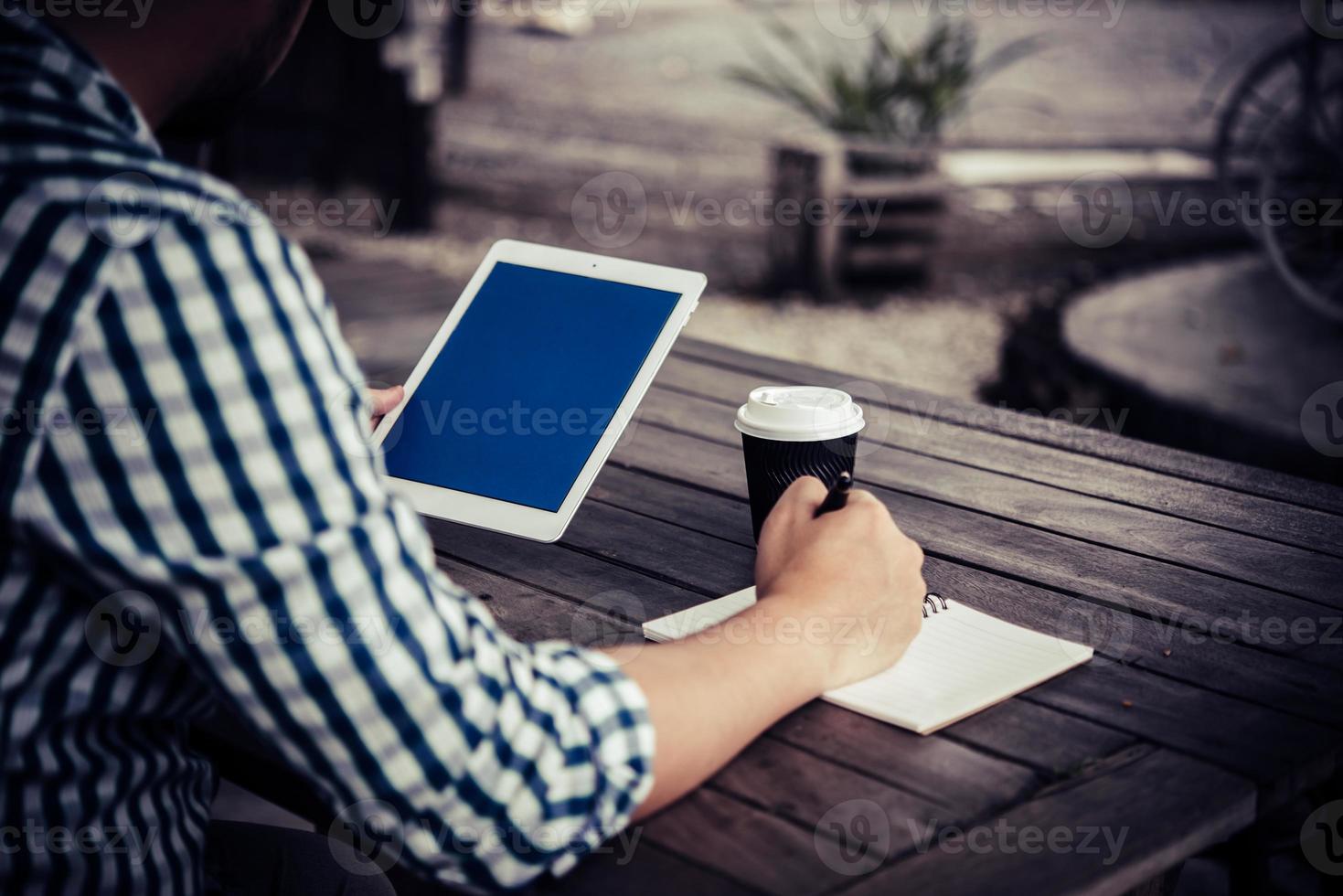 jonge man met behulp van digitale tablet terwijl het drinken van koffie om thuis te zitten tuin foto