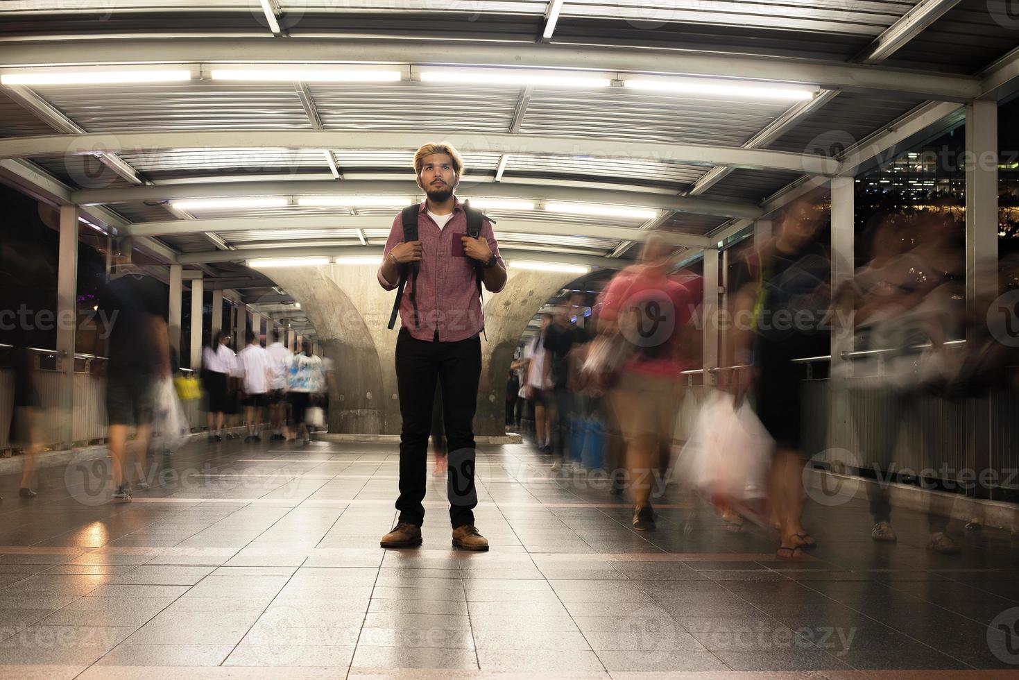knappe bebaarde man met rugzak staande op straat 's nachts reizen foto