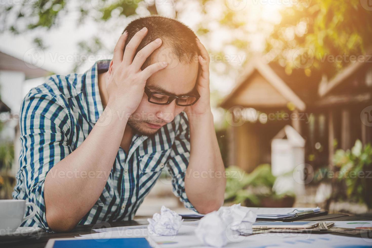 benadrukt zakenman met papieren en grafieken om thuis aan tafel te zitten foto