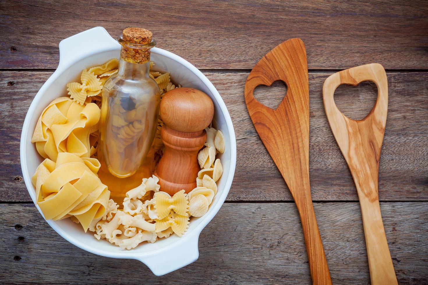 kom pasta met olie en houten keukengerei foto