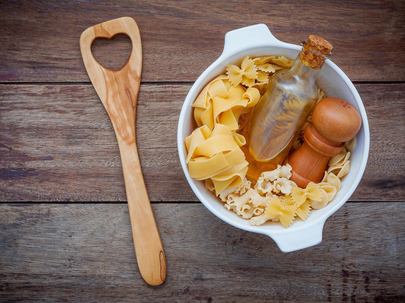 pasta, olie en peper in een kom met een houten gebruiksvoorwerp foto