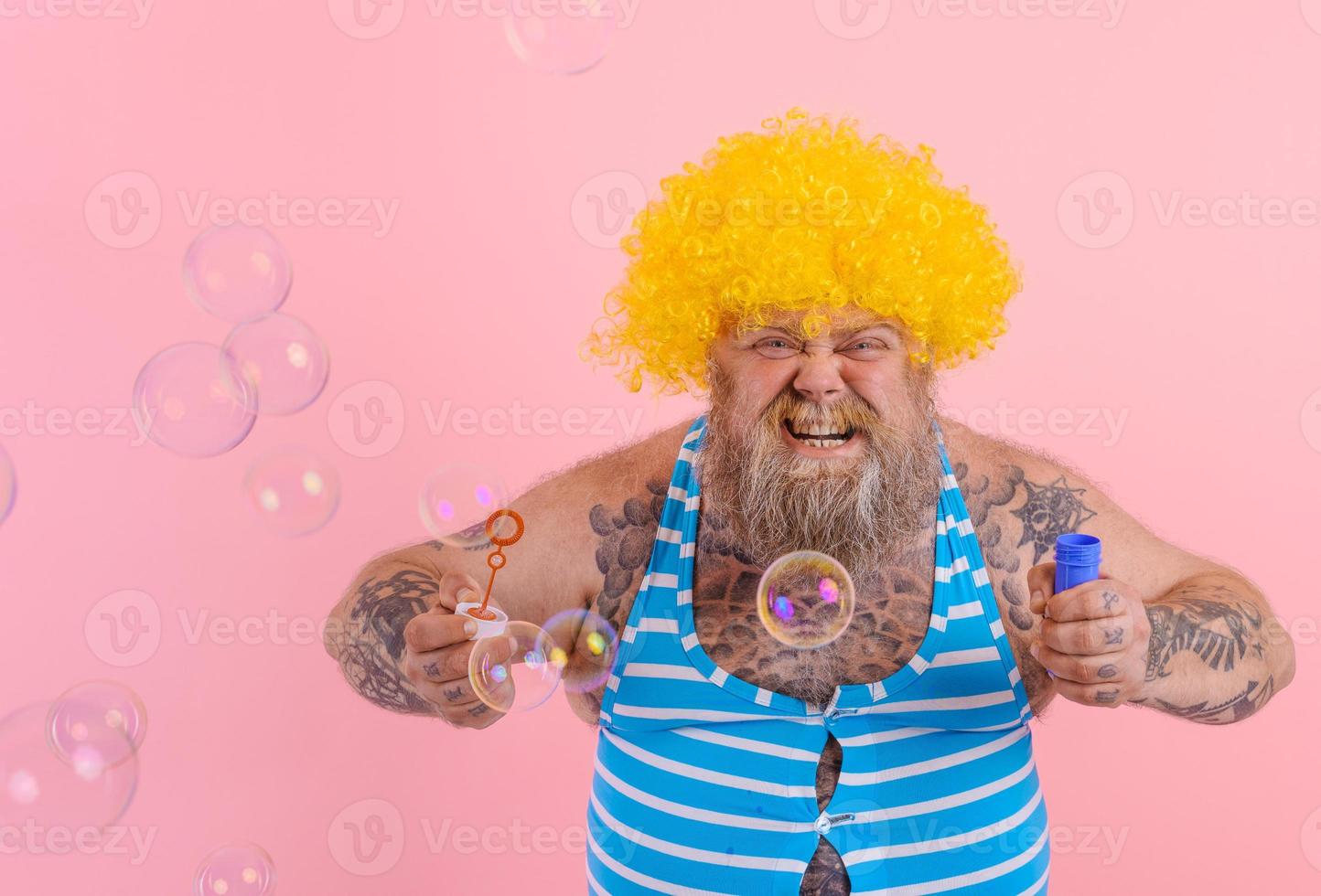 gelukkig Mens met geel pruik in hoofd Speel met bubbels zeep foto