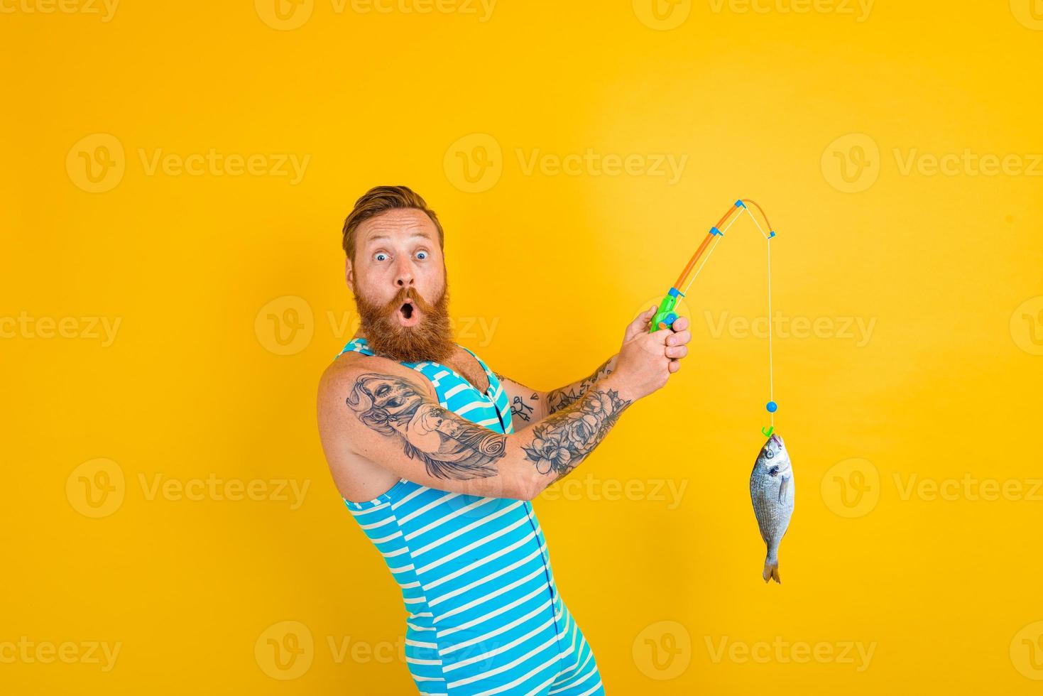 Mens met baard en zwempak gevangen een vis foto