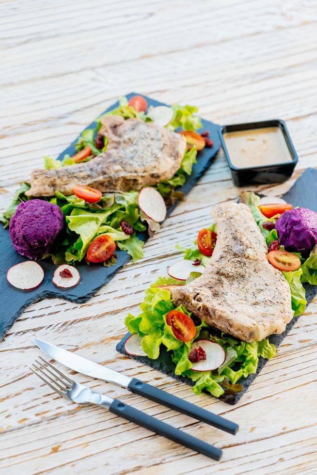 gegrilde bbq karbonade vlees steak op zwarte plaat met groenten foto