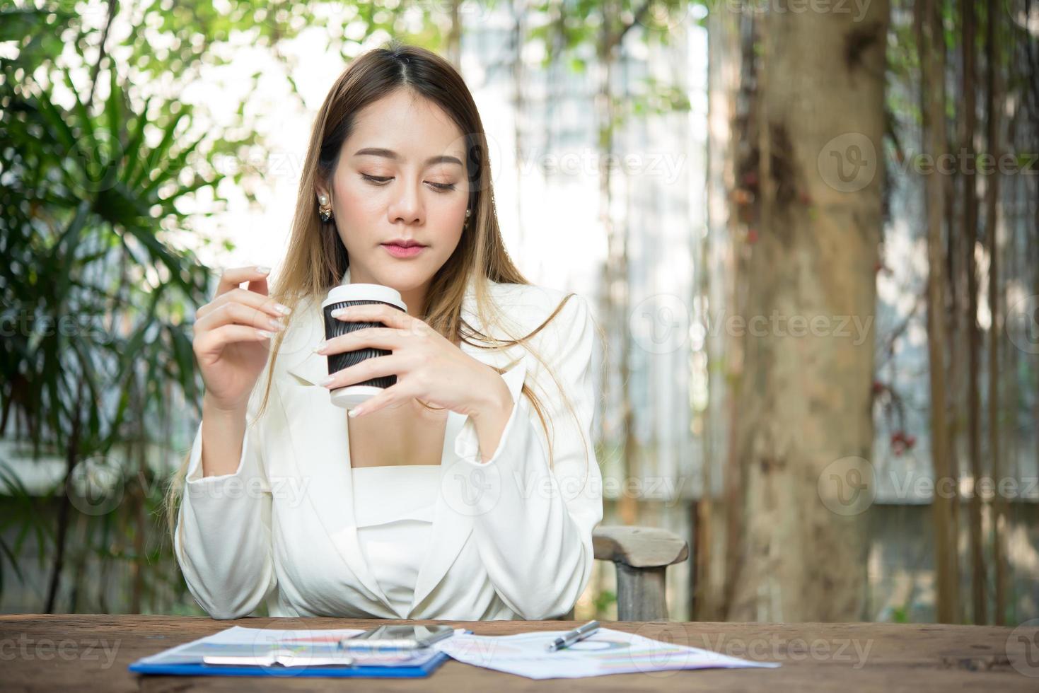 jonge zakenvrouw zitten in een kantoor een kopje koffie drinken foto