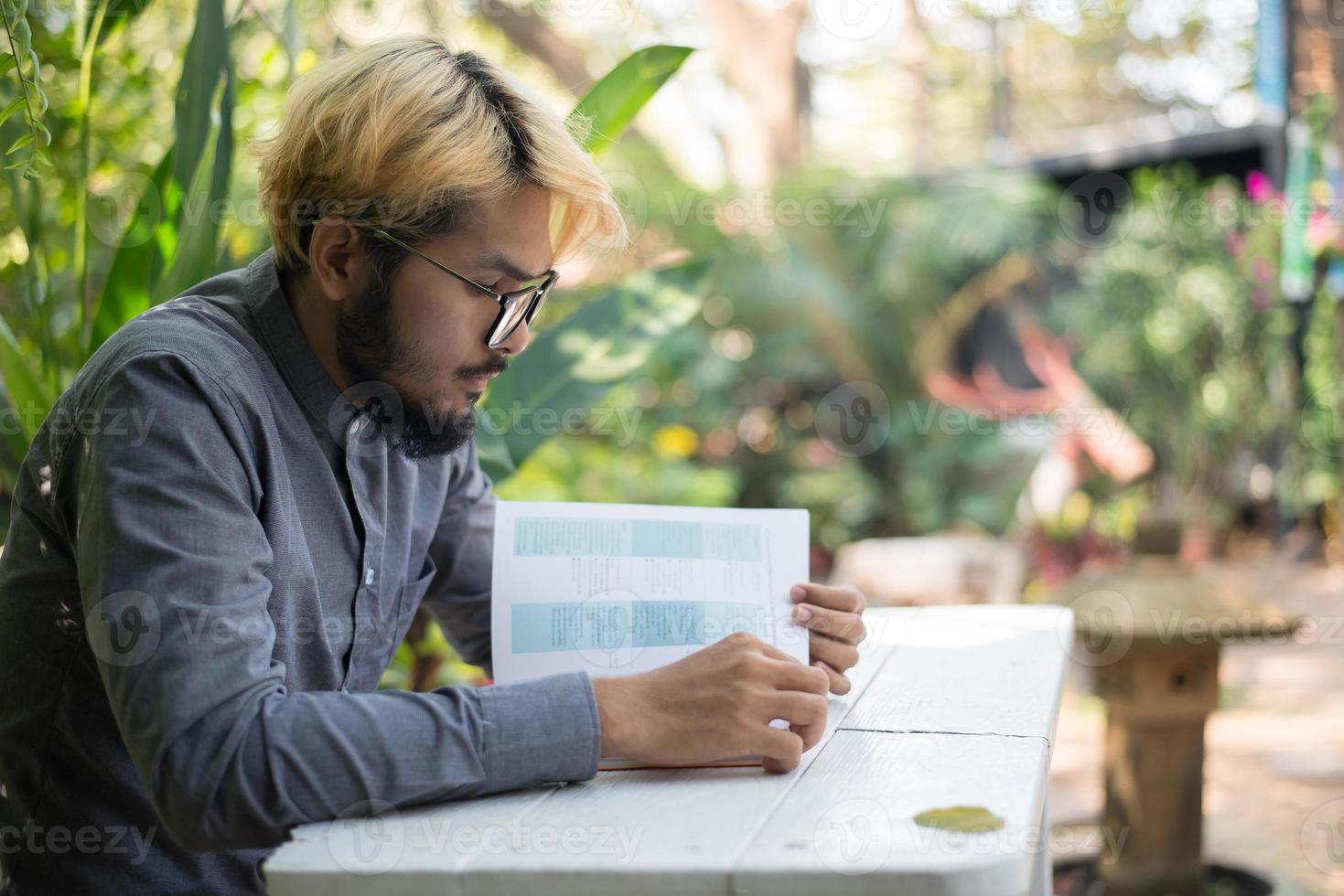 jonge hipster bebaarde man lezen van boeken in eigen tuin met de natuur foto