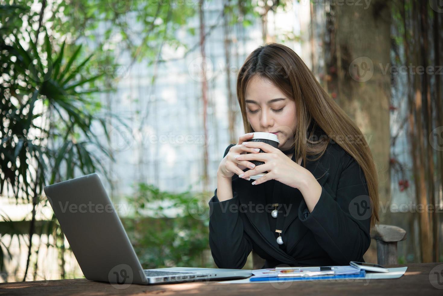 zaken vrouw praten over de telefoon en met behulp van haar laptop zittend op een tafel thuis foto