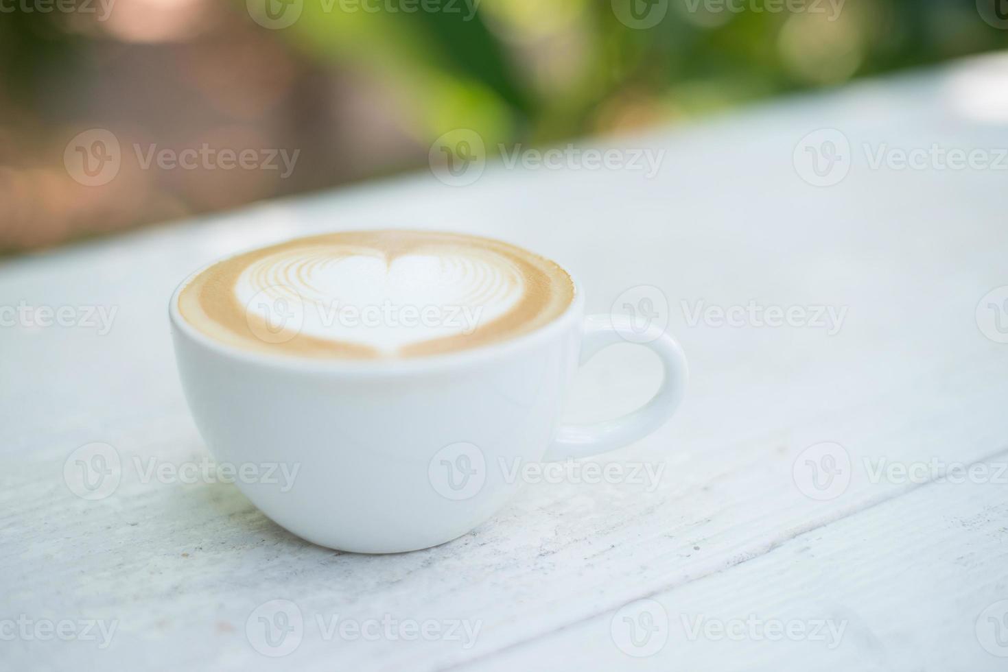 kopje latte art hartvorm koffie op witte tafel. foto