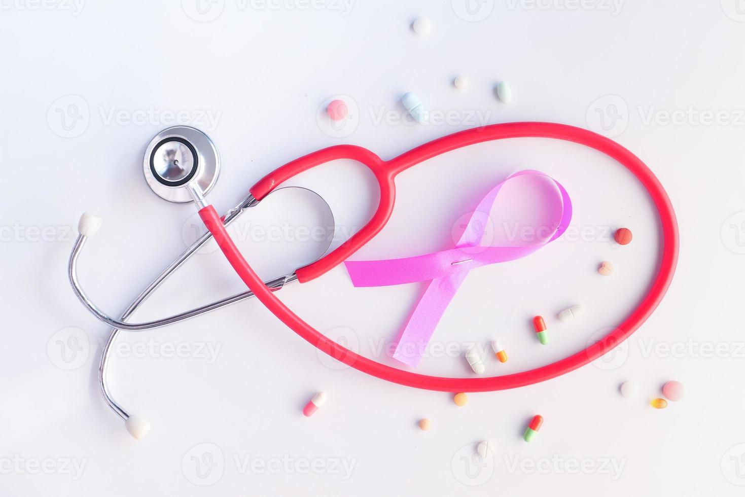 roze lint, pillen en een stethoscoop op witte achtergrond foto