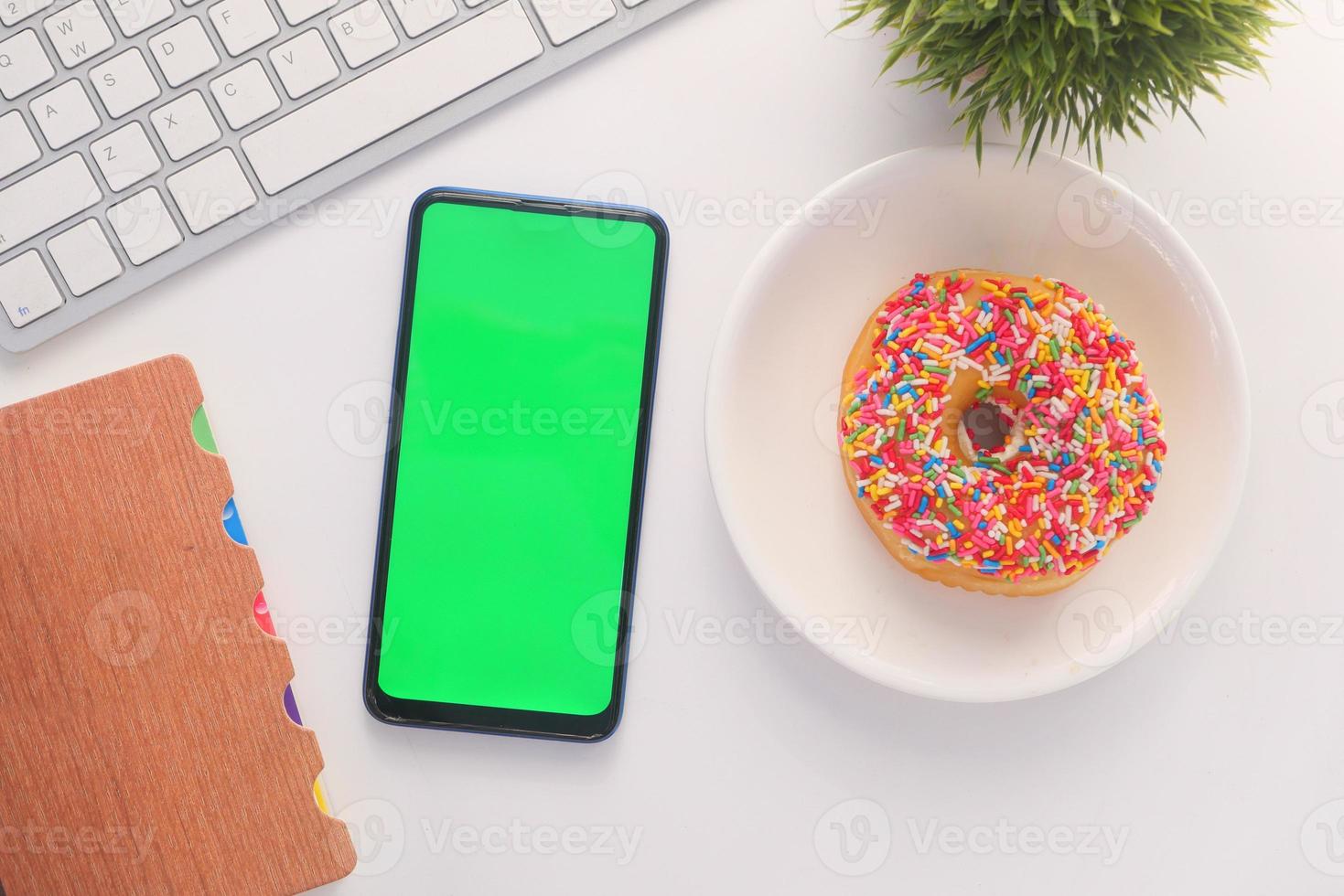 bovenaanzicht van slimme telefoon en donut op het bureau foto