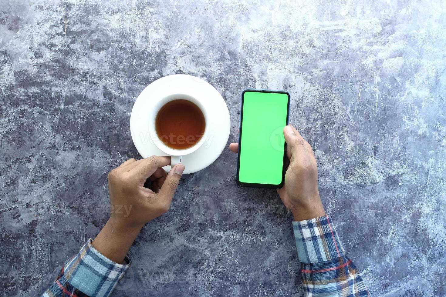 slimme telefoon met groen scherm en een kopje koffie foto