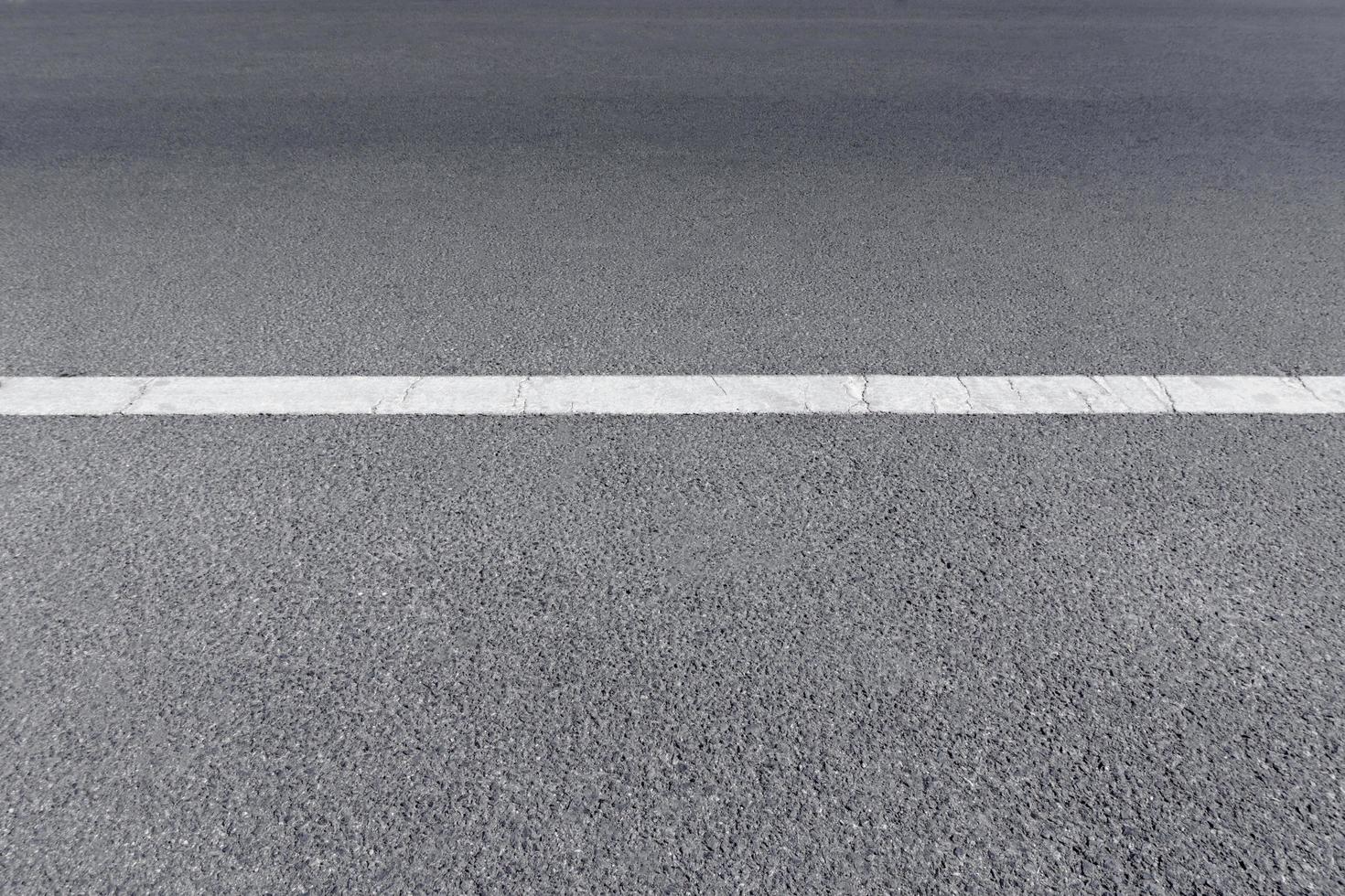 een verharde straatweg met witte verkeerslijnen foto