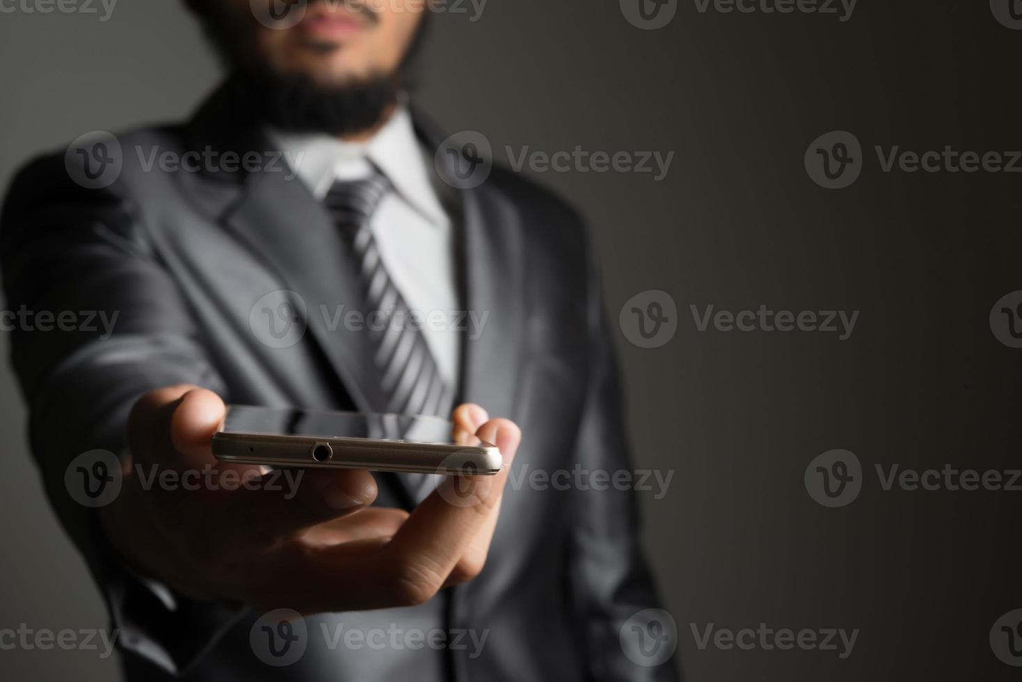 portret van zakenman met smartphone tegen zwarte achtergrond foto
