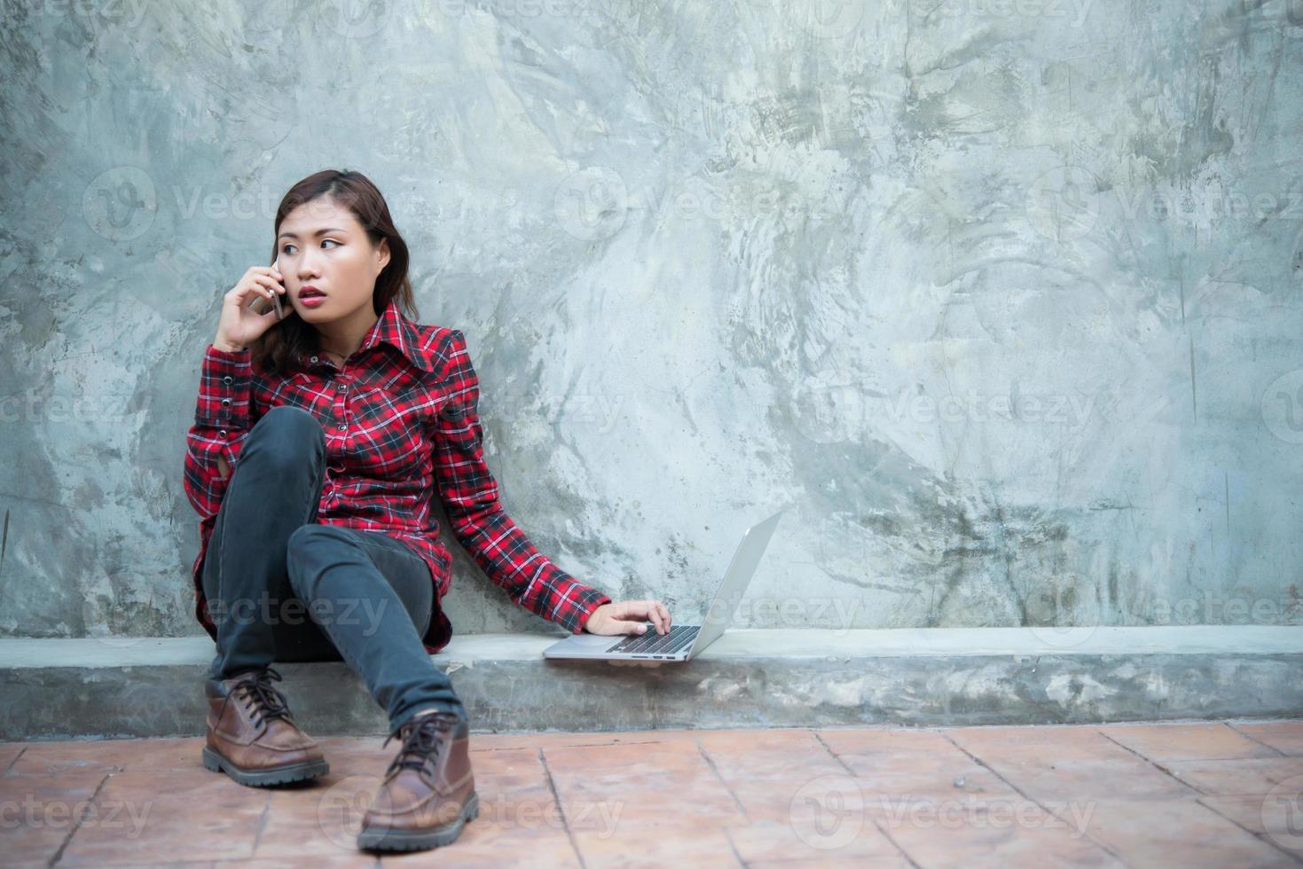 jonge hipster vrouw in coole outfit, zittend op de grond en praten aan de telefoon foto