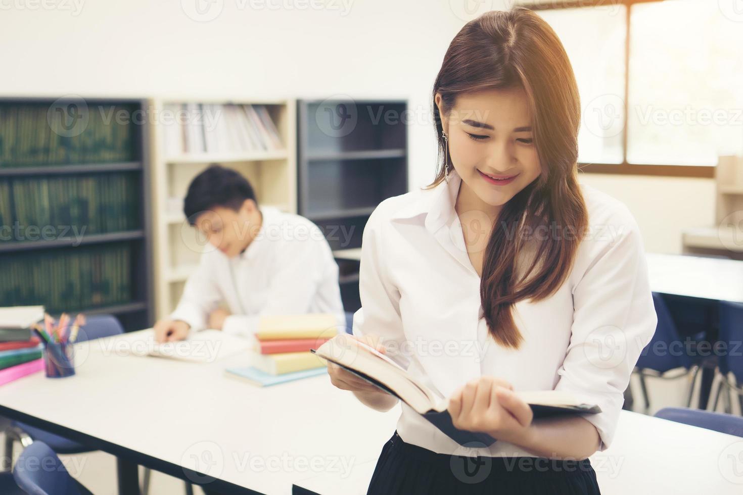 jonge Aziatische studenten in de bibliotheek die een boek lezen foto