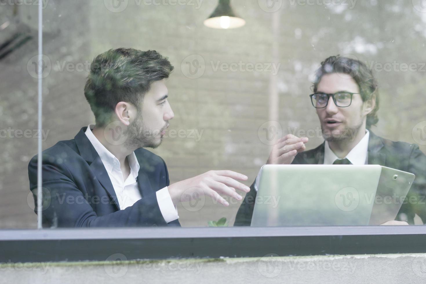 twee jonge zakenlieden die laptop gebruiken die op kantoor samen werken foto