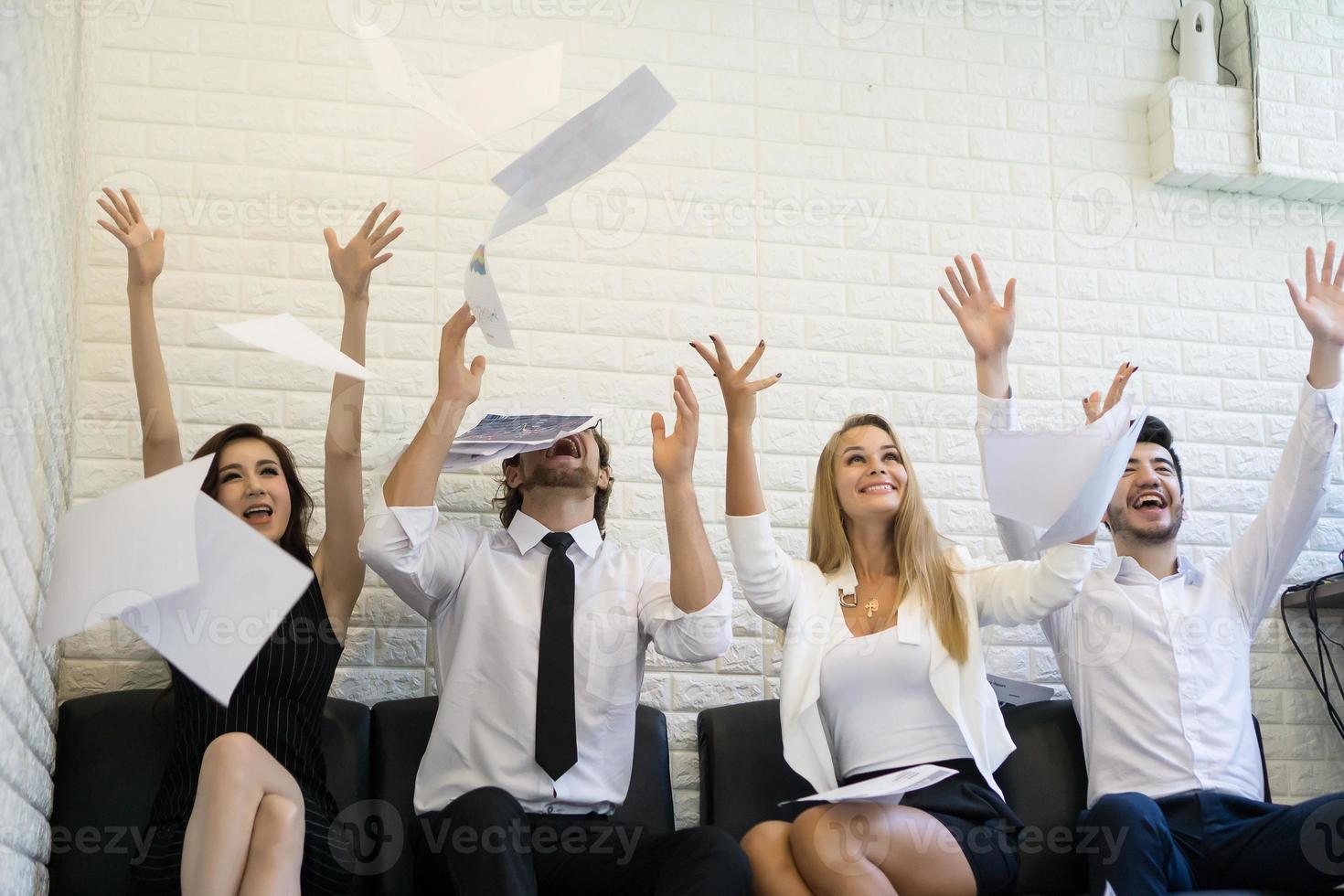 gelukkige zakenmensen die documenten in de lucht gooien foto