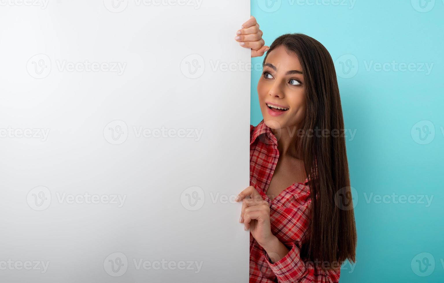 brunette vrouw looks een wit blanco spandoek. vrij ruimte voor uw tekst foto