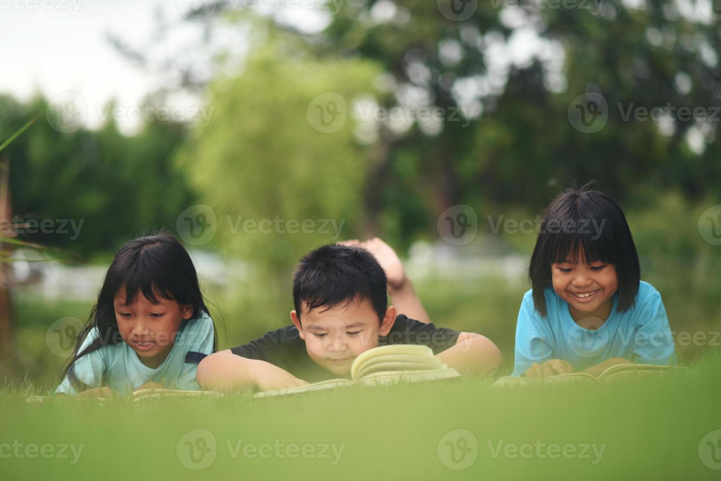 groep van kinderen aan het liegen lezing Aan gras veld- foto