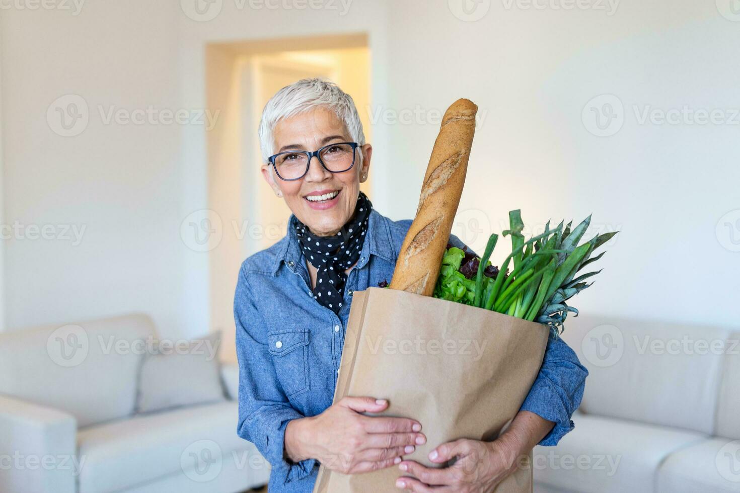 gezond positief gelukkig vrouw Holding een papier boodschappen doen zak vol van fruit en groenten. portret van mooi senior vrouw kruidenier boodschappen doen zak met groenten Bij huis foto