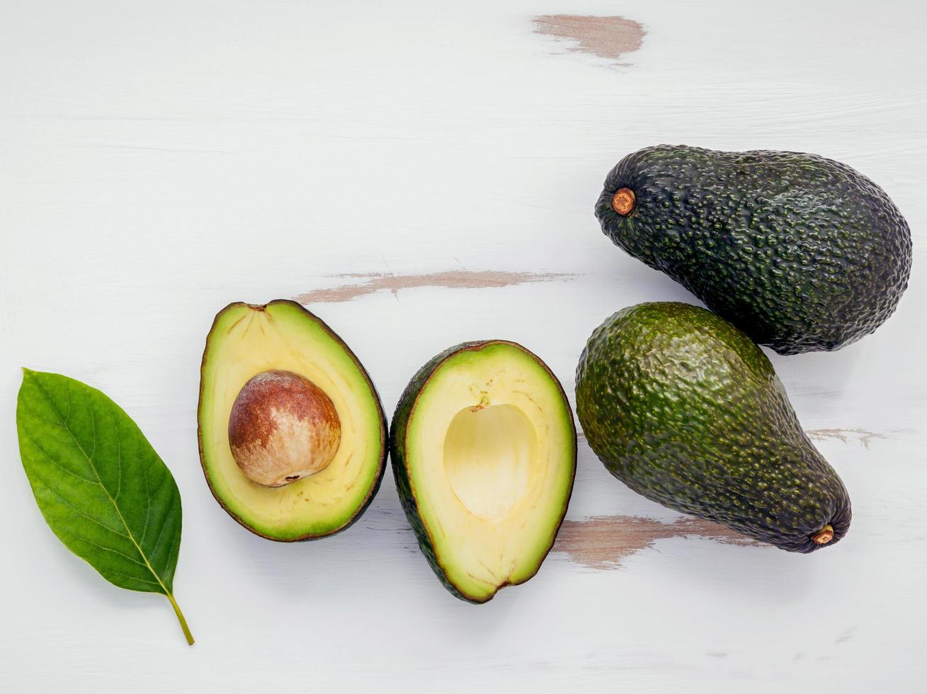 bovenaanzicht van hele en gehalveerde avocado's foto